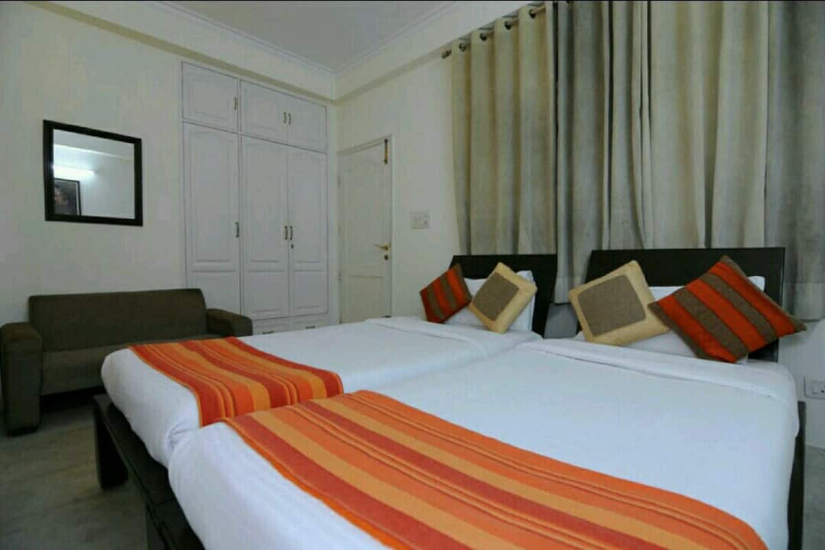 A hotel room with two beds, a sofa, and a wardrobe.