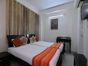 A hotel room with two beds, a desk, and a TV. - Mehra Residency at the Airport (New Delhi)