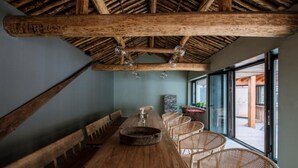 A dining area with a long wooden table, wicker chairs, and a rustic ceiling with exposed beams and hanging light fixtures. - Yi She Mountain Inn (Changping)