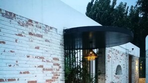A modern outdoor patio area with a brick wall, a wooden deck, and a seating area with a table and chairs. - Yi She Mountain Inn (Changping)