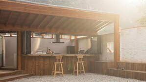 A modern kitchen with wooden bar stools, a large island, and a view of a mountainous landscape. - Yi She Mountain Inn (Changping)