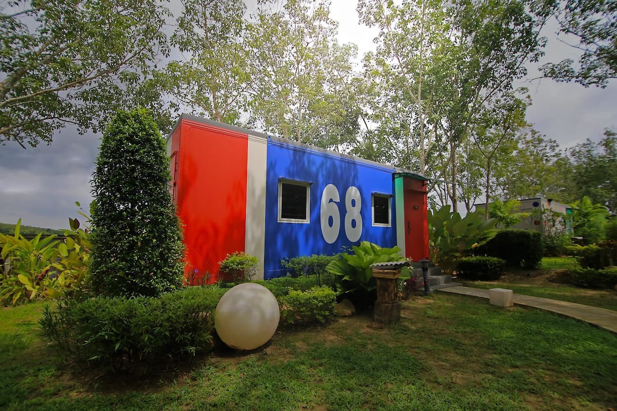 A colorful building with the number 68, surrounded by greenery and a well-maintained garden.