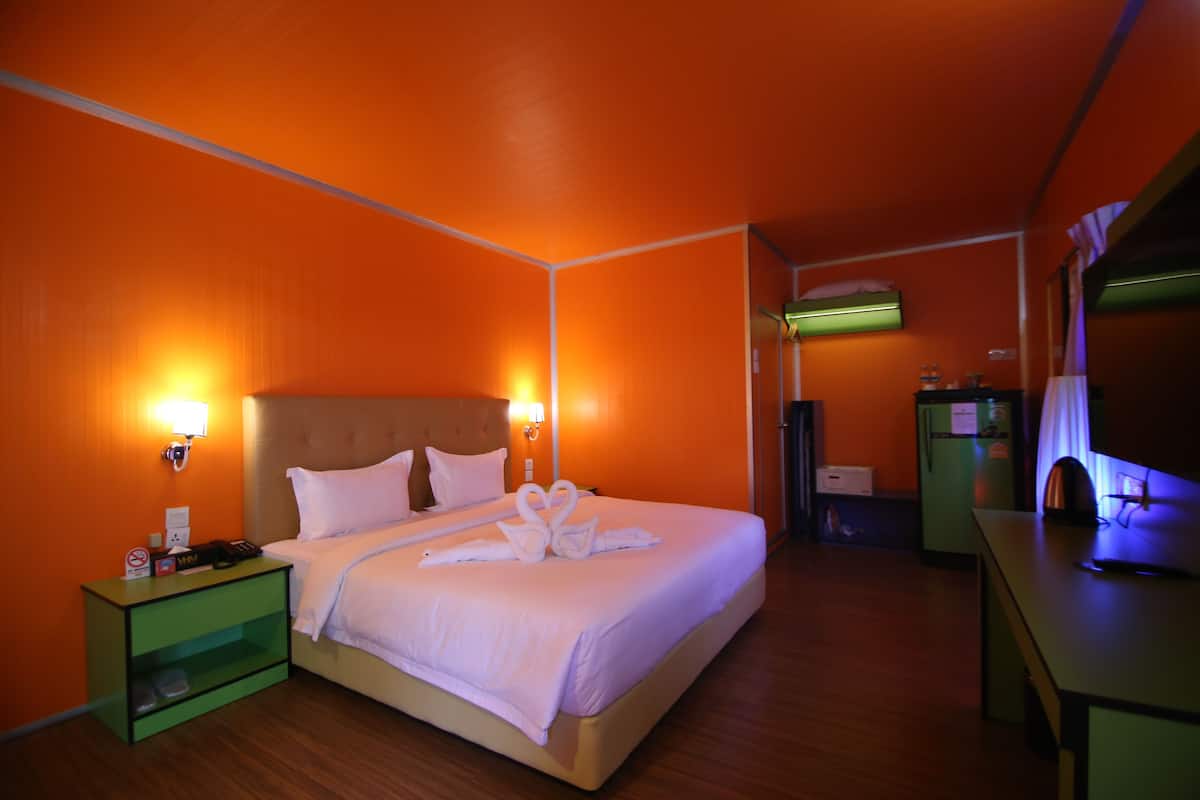 A hotel room with a bed, a nightstand, a desk, and a refrigerator.
