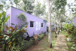 A row of purple mobile homes numbered 28, surrounded by lush greenery and a stone pathway. - VJ Villa & Container Stay (Sadao)