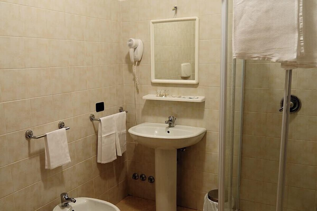 A bathroom with a toilet, bidet, sink, and glass-enclosed shower.