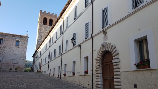 Una calle adoquinada con edificios históricos, una torre y un arco de piedra.