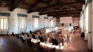 Un amplio salón con techo alto y vigas a la vista, amoblado con sillas y mesas dispuestas para una reunión o evento.