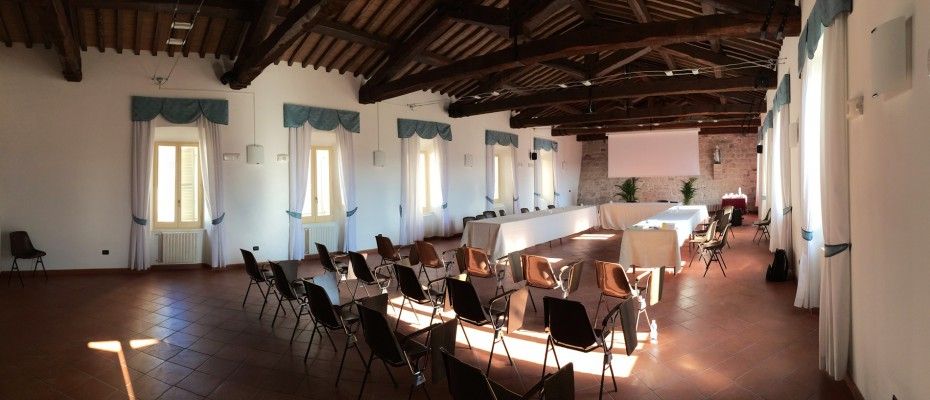 A spacious hall with a high ceiling and exposed beams, furnished with chairs and tables arranged for a meeting or event.