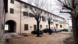 Un edificio con fachada color beige, varias ventanas y un estacionamiento con coches.