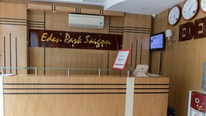 A reception desk with a sign reading "Eden Park Saigon," a mounted television, and a coffee machine. - RedDoorz Plus near SECC D7 (Ho Chi Minh City)