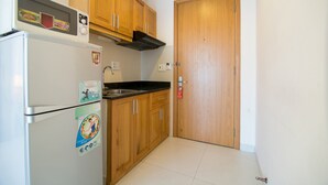 A compact kitchen with wooden cabinets, a built-in microwave, and a stainless steel sink. - RedDoorz Plus near SECC D7 (Ho Chi Minh City)