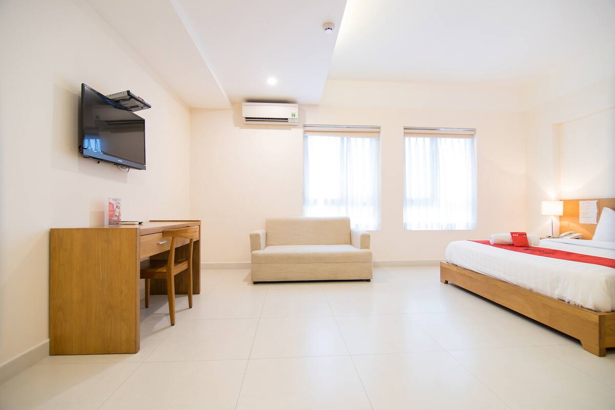 Ein Hotelzimmer mit Bett, Schreibtisch, Stuhl und Fernseher.