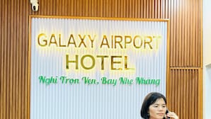 Una mesa de recepción con un cartel que dice 'GALAXY AIRPORT HOTEL' y 'Nghi Tron Ven, Bay Nhe Nhang'.