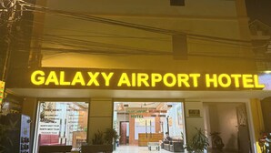 Exterior del Galaxy Airport Hotel, con un cartel claro, una zona de recepción y un área de estar al aire libre.