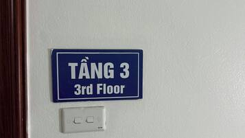 A blue sign with white text indicating 'TÂNG 3 3rd Floor' above a white electrical switch.