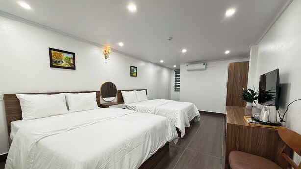Habitación de hotel con dos camas, un escritorio con televisor y una silla.