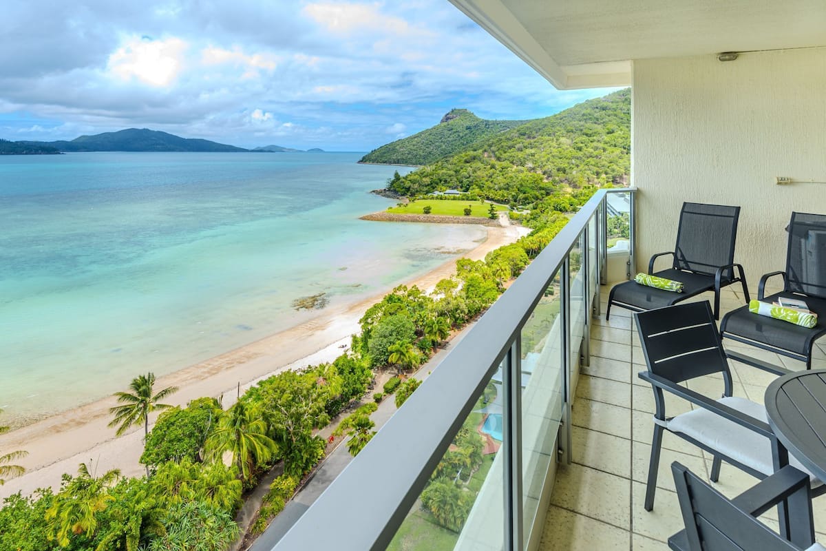 Un balcone con vista sulla spiaggia e sull'oceano, dotato di tavolo e sedie.