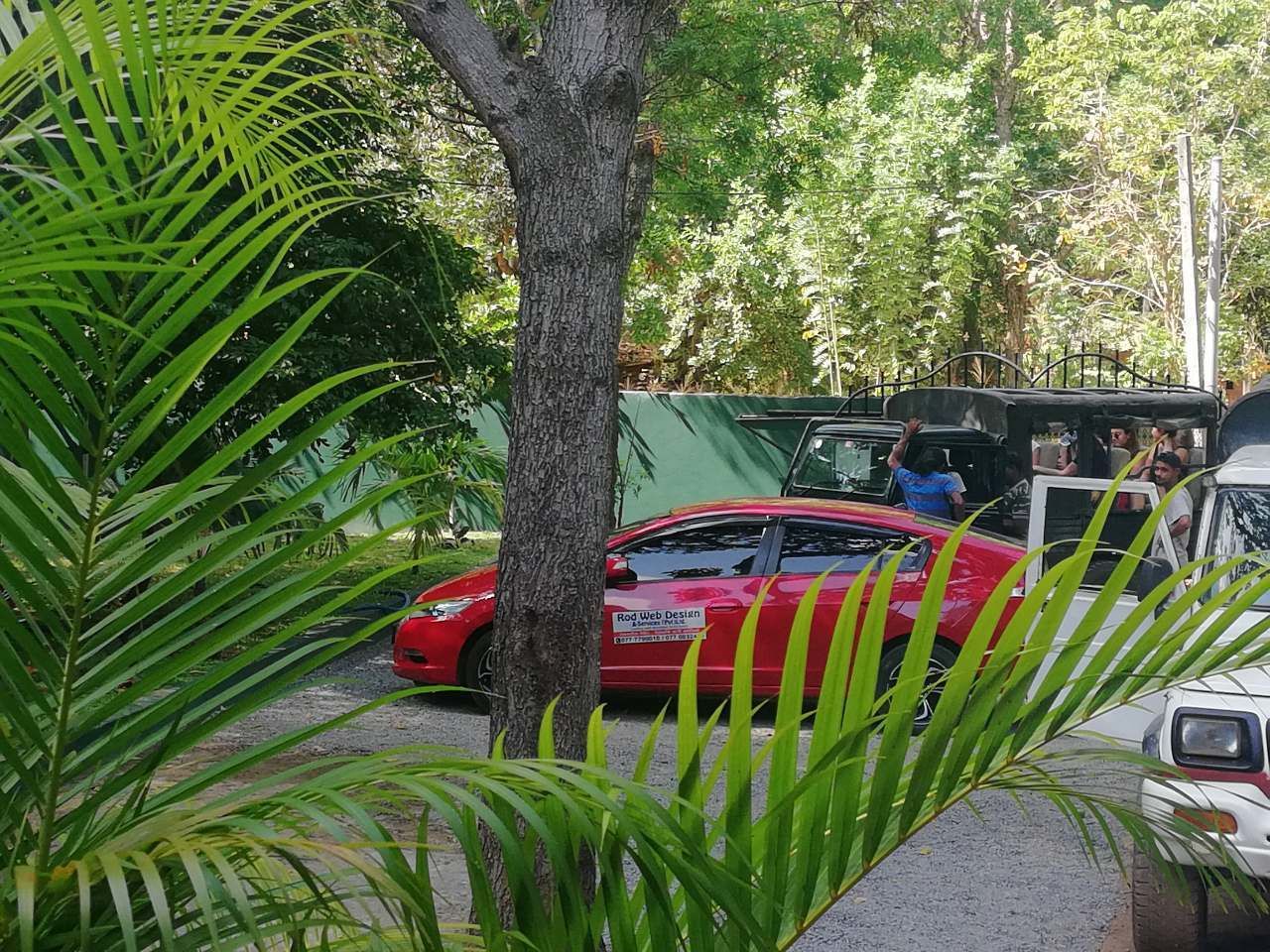 Punainen auto oli pysäköitynä rakennuksen eteen, ja rakennuksen yläpuolella oli vihreä markiisi.