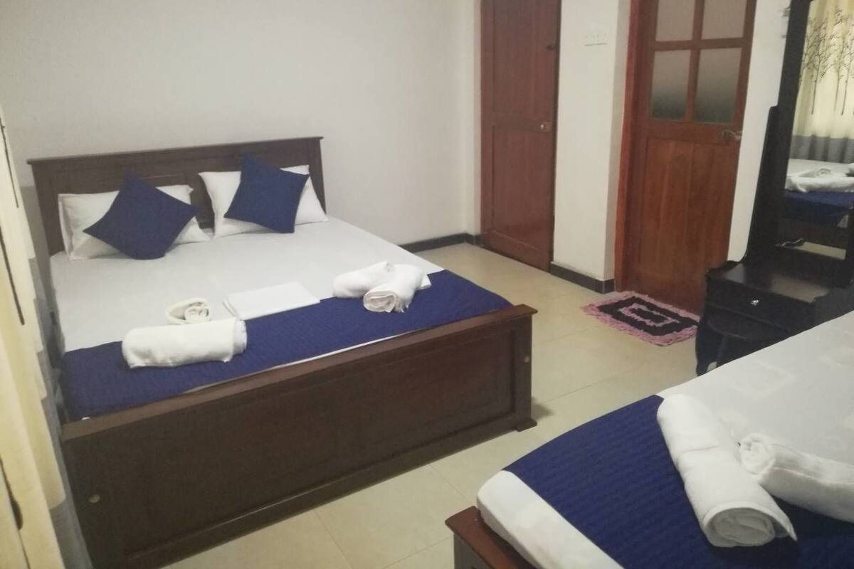 A hotel room with two beds, a wooden headboard, and a wardrobe.