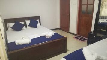 Une chambre d’hôtel avec deux lits, une tête de lit en bois et une armoire.