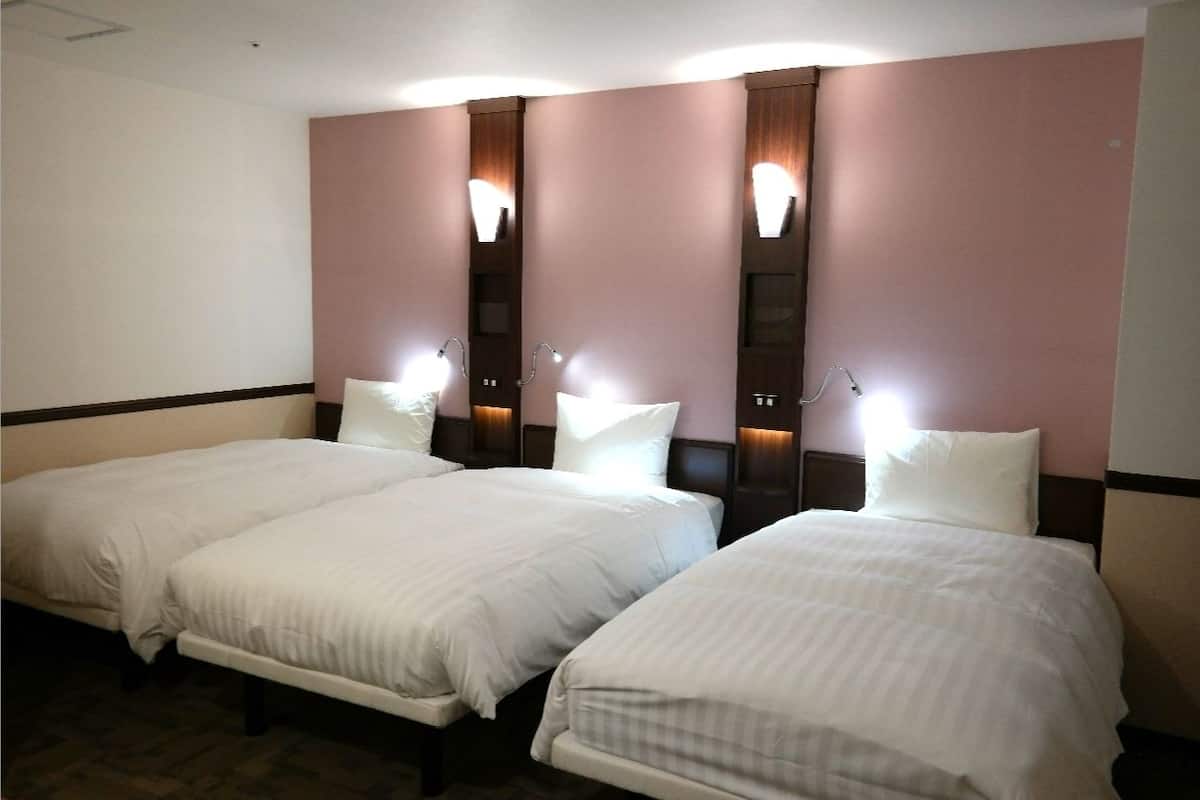 A hotel room with two single beds, each with a headboard and nightstands.