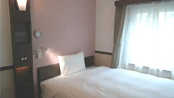 Habitación de hotel con cama, teléfono en la mesita de noche, reloj de pared y ventana con cortinas.