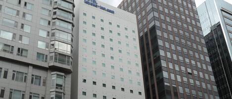 A high-rise hotel with multiple floors, a prominent sign, and surrounding modern buildings.