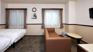 A hotel room with two beds, a sofa, a small table, a clock, and a television on the wall.