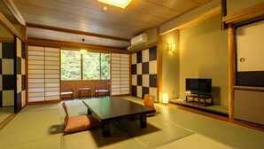A traditional Japanese room with tatami flooring, a low table, chairs, a television, and sliding doors. - Yumoto Komachikan (Yugawara)