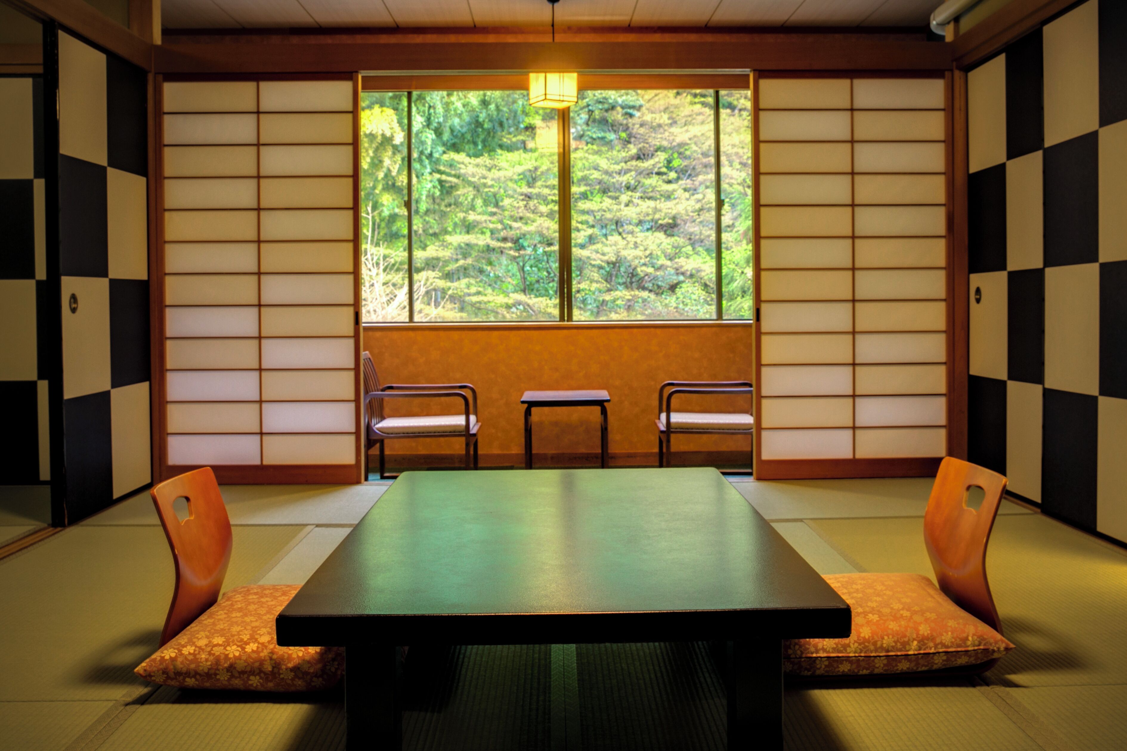 A traditional Japanese room with tatami flooring, a low table, and three chairs.