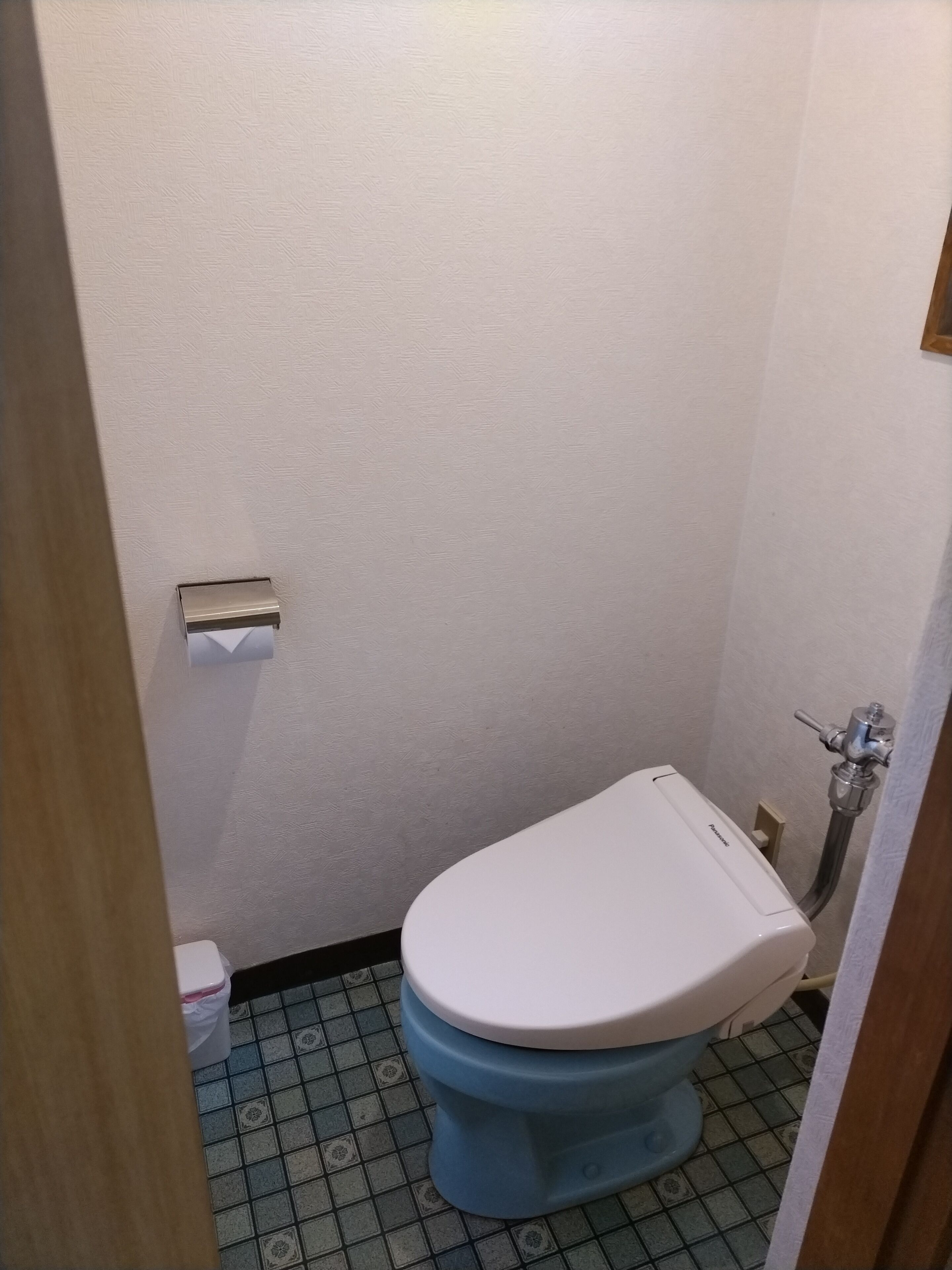 A small bathroom with a toilet, a toilet paper holder, and a shower area.