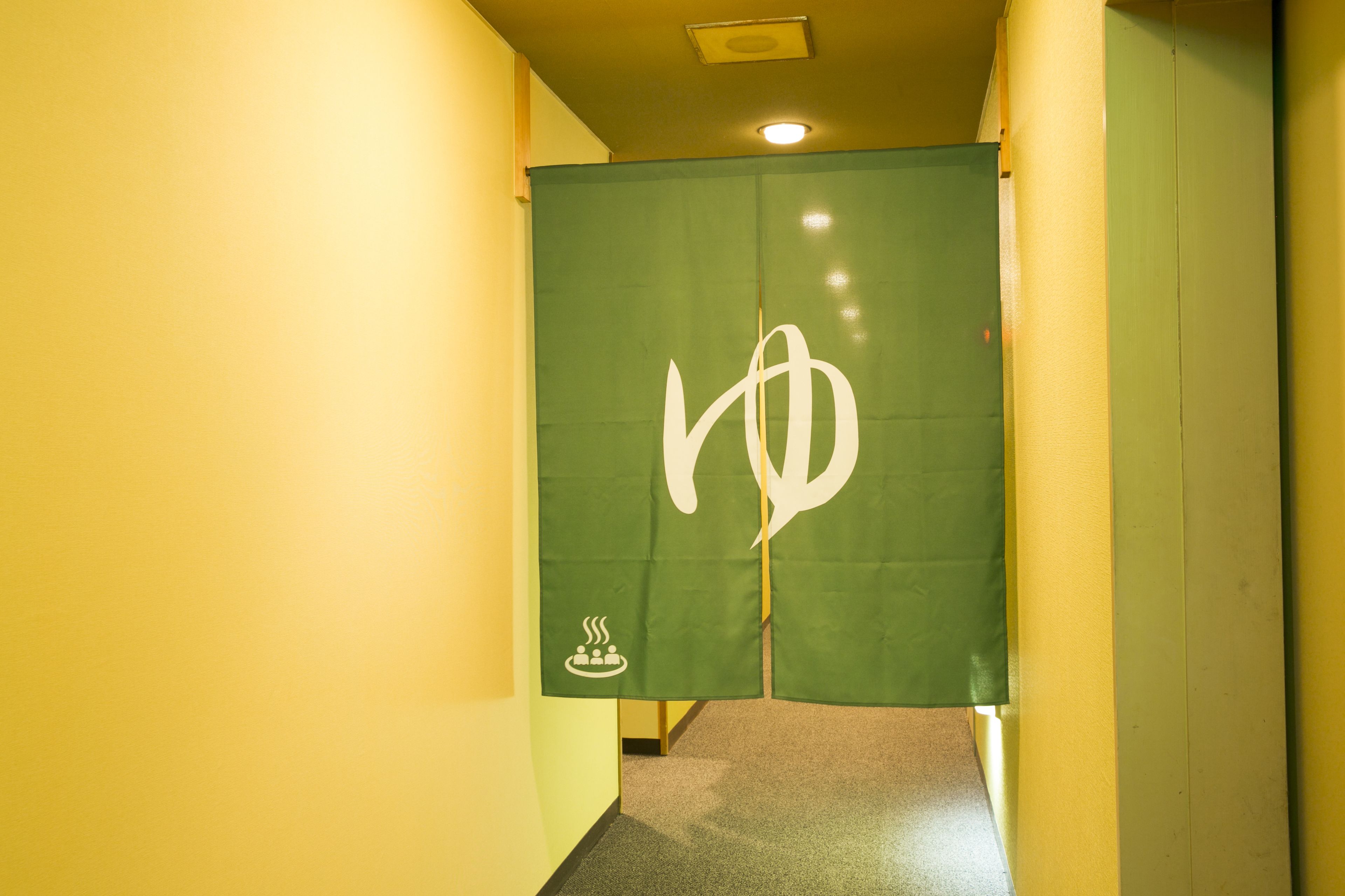 A hallway with a green partition featuring a white symbol.