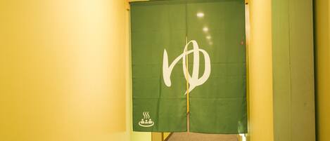 A hallway with a green partition featuring a white symbol.