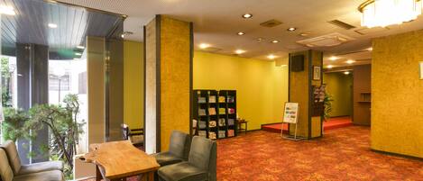 A lobby with a wooden table and chairs, a bookshelf, and a carpeted floor.