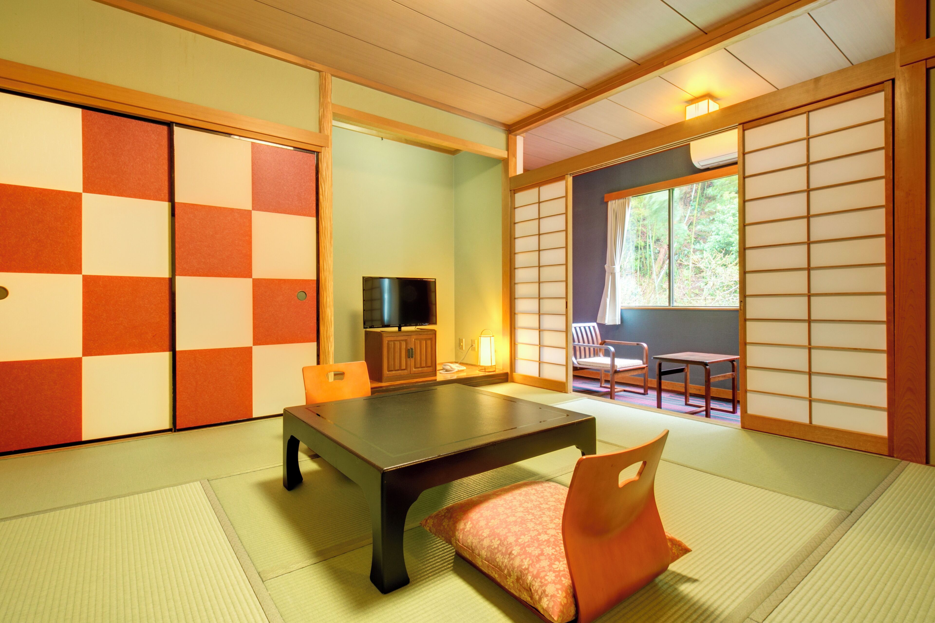 A traditional Japanese room with tatami flooring, a low table, chairs, and sliding doors.