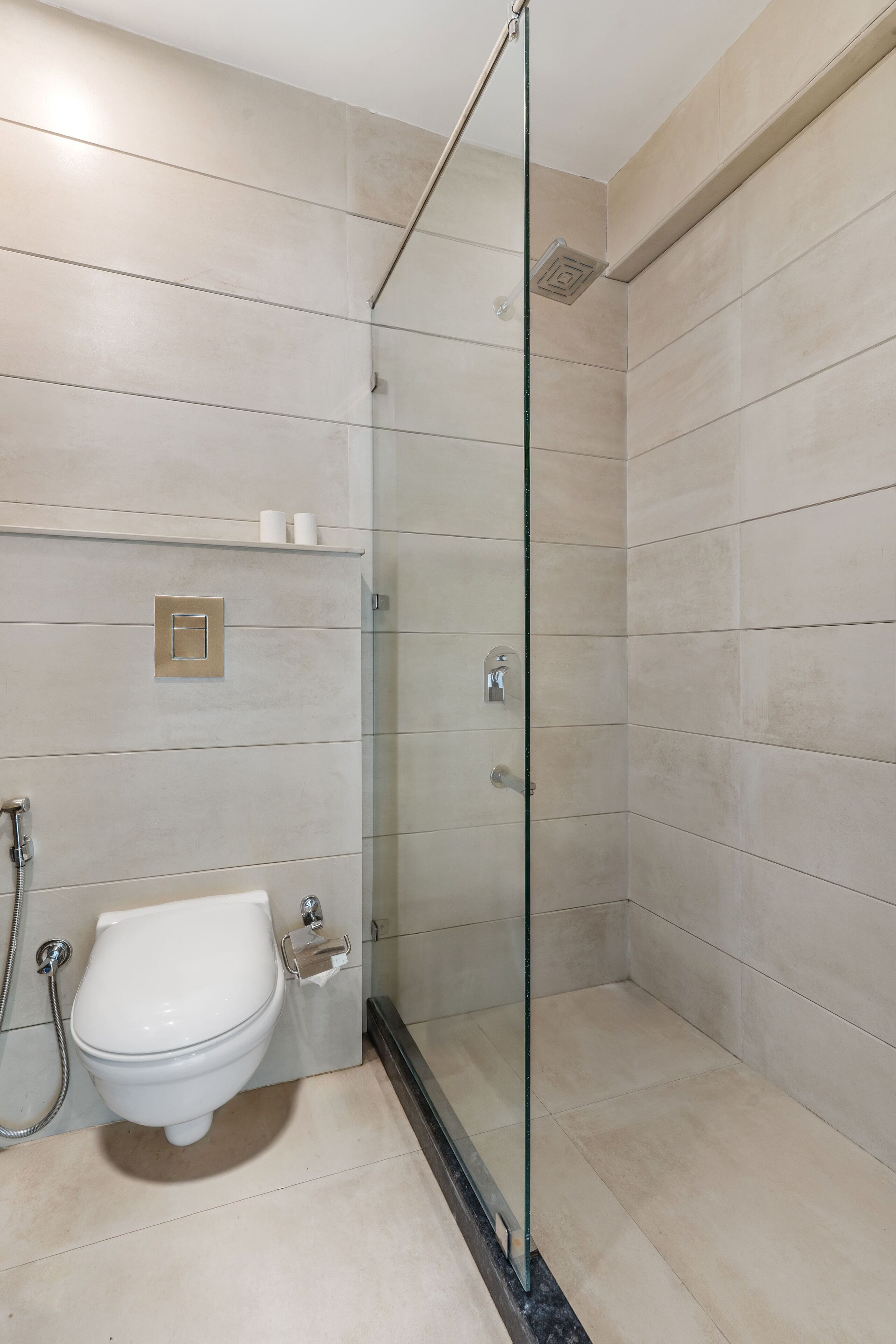 Ein modernes Badezimmer mit einer Duschkabine, einer Toilette und einem Ablagefach mit Pflegeprodukten.