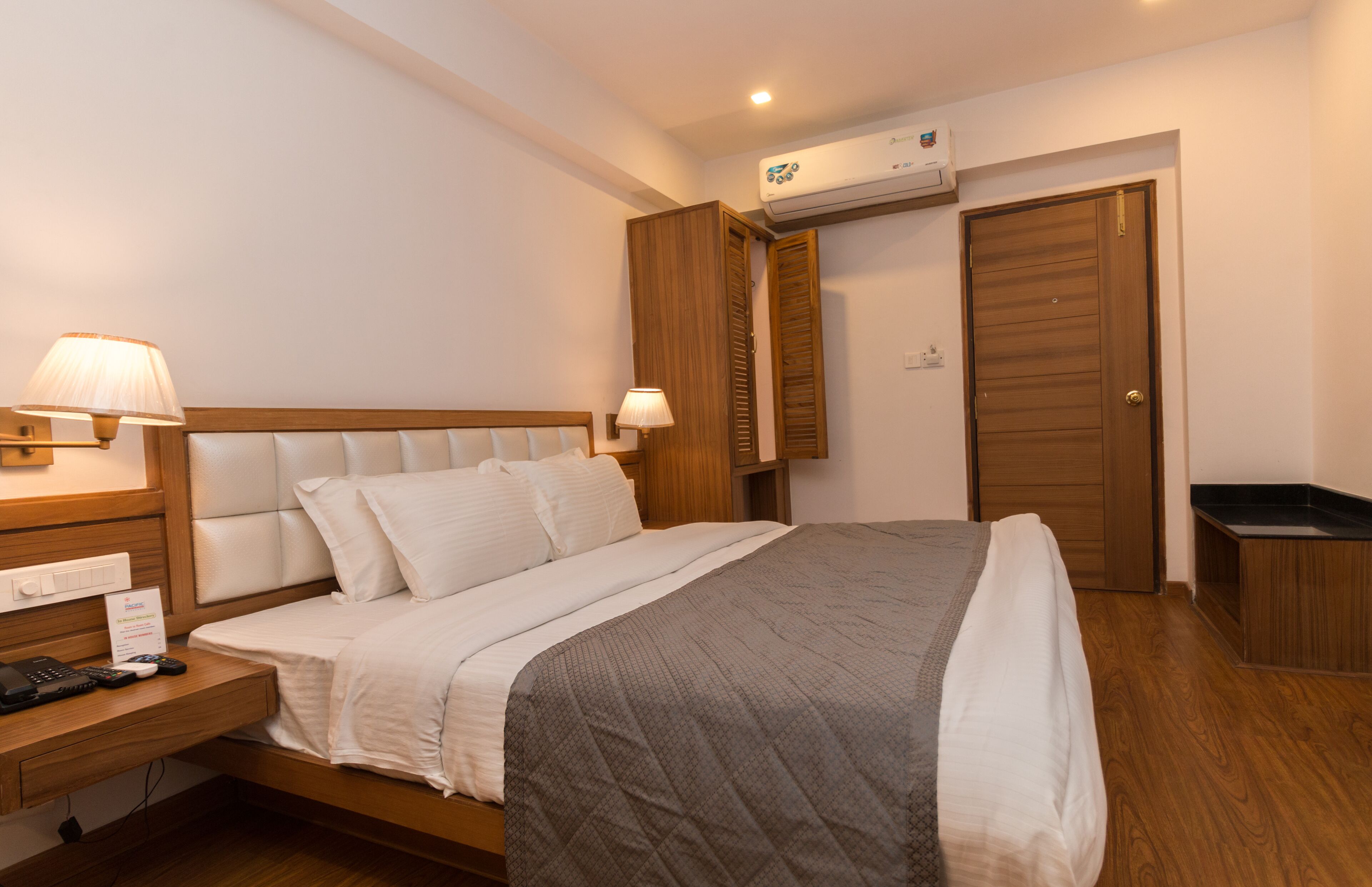 A bedroom with a bed, bedside tables, a wardrobe, and an air conditioning unit.