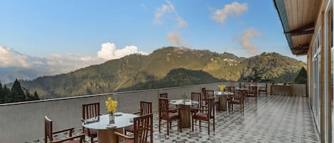 Une terrasse dotée de tables et de chaises, offrant une vue sur un paysage montagneux.
