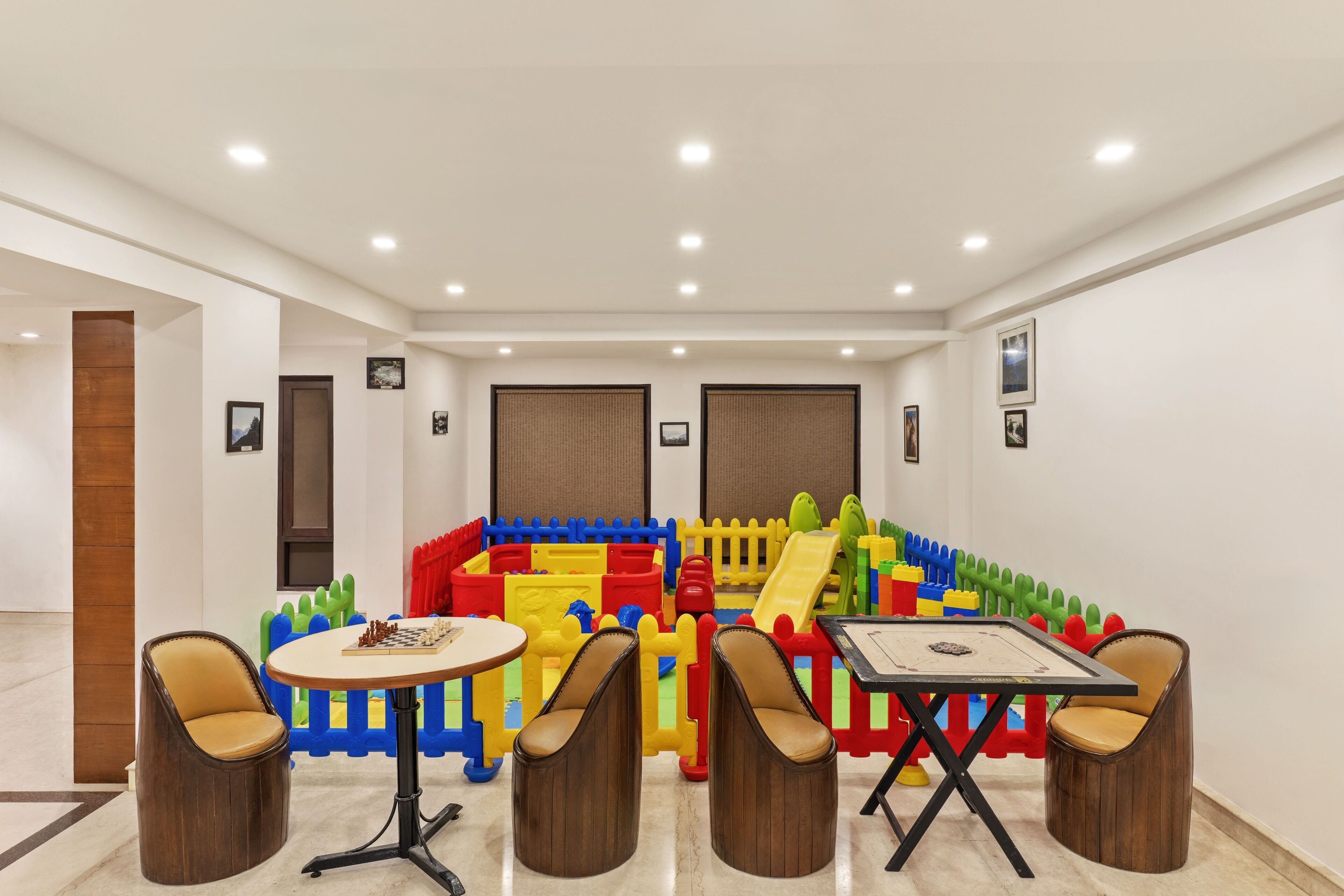 Espaço de recreação com estruturas coloridas e duas mesas redondas com cadeiras.
