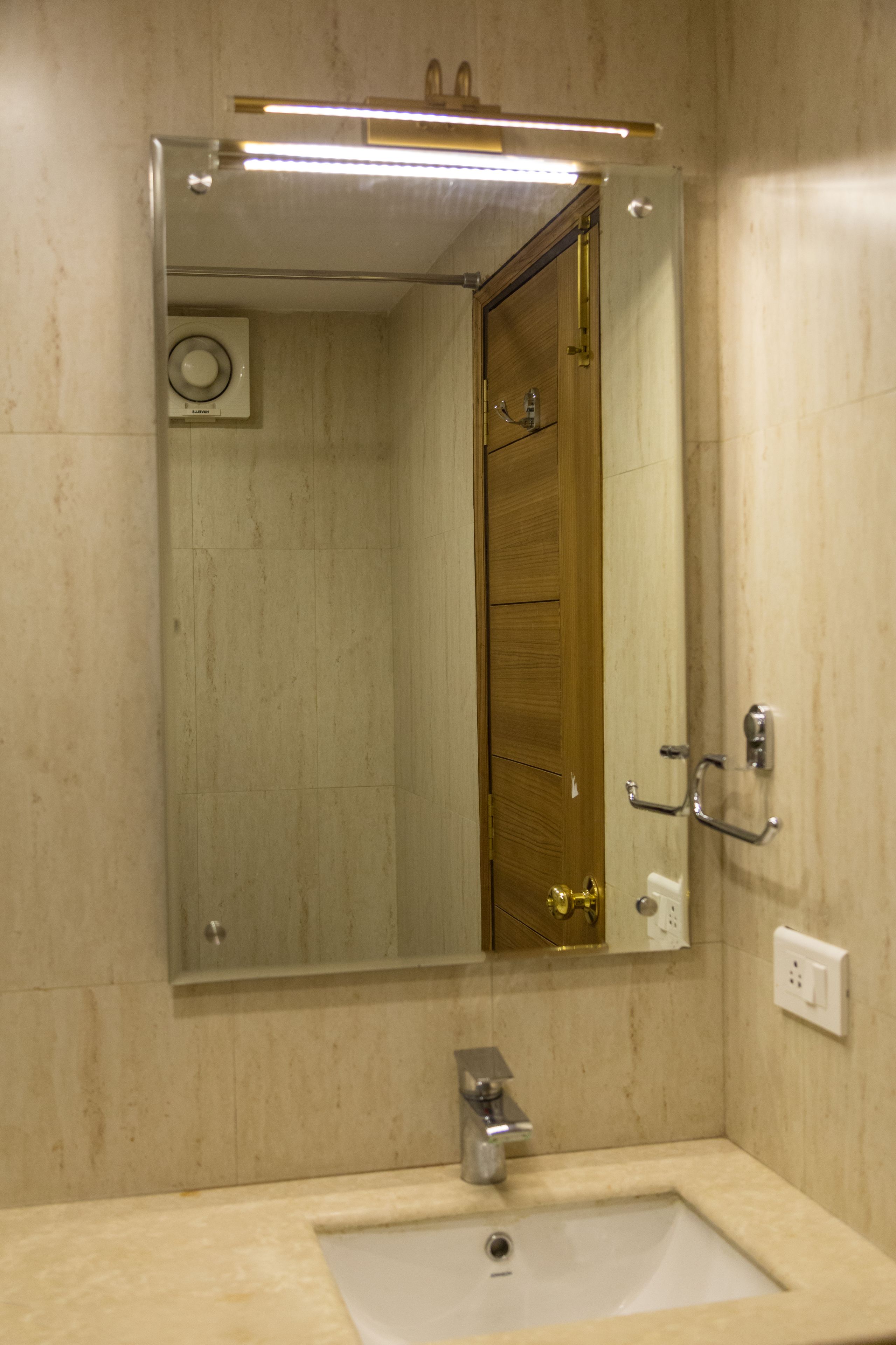 A bathroom with a sink, mirror, and a wooden door.