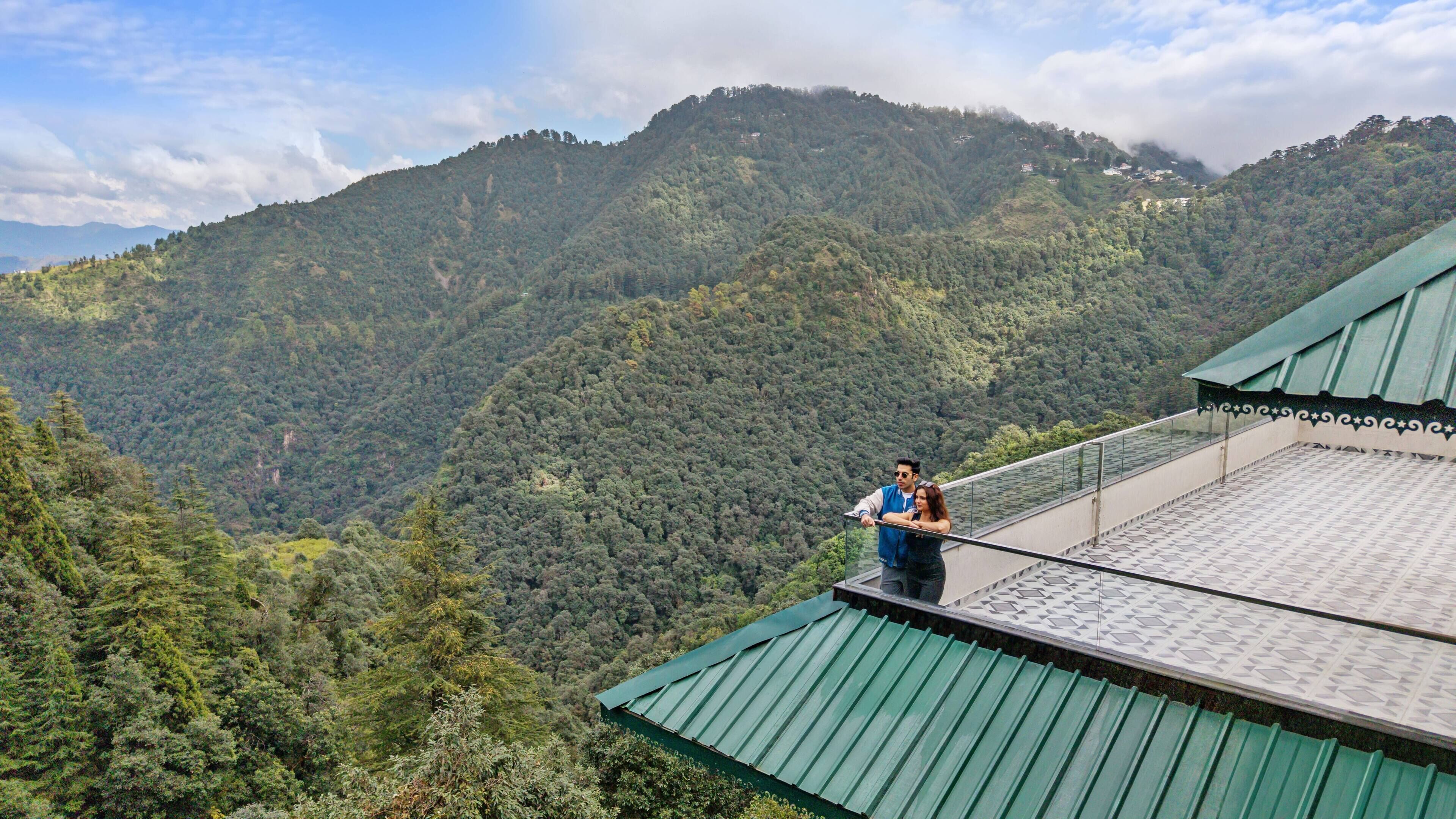 A view from a balcony overlooking a forested mountain range.