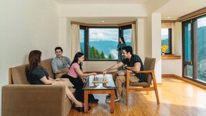 Um quarto com uma janela grande, uma mesa de centro de madeira e um sofá.