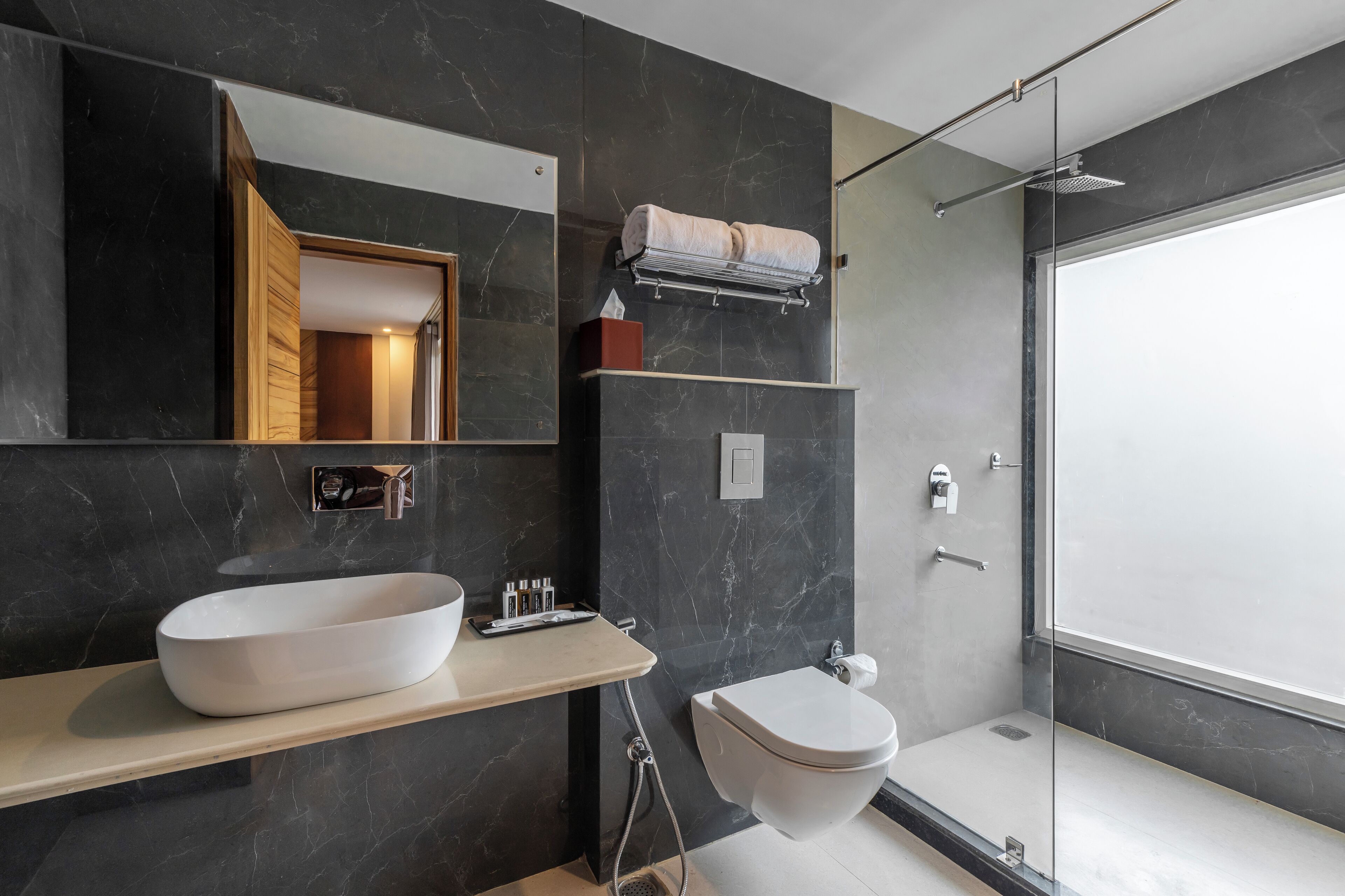 Une salle de bain moderne avec un grand miroir, un lavabo blanc et une douche à parois de verre.