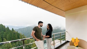 Uma varanda com vista para uma cadeia montanhosa coberta por floresta.