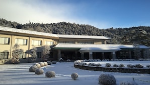 A building with a snow-covered courtyard, surrounded by snow-covered trees and a mountainous backdrop. - Nikko Toshogu Koyoen (Nikko)