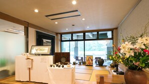 A traditional Japanese room with tatami flooring, a wooden stage with a display, and a large window with a view of greenery. - Nikko Toshogu Koyoen (Nikko)