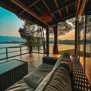 A covered outdoor seating area with a view of a lake and mountains. - Green View Resort (Vang Vieng)