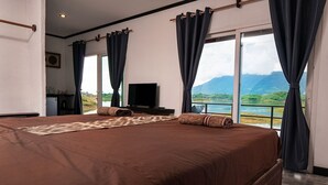 Une chambre avec un grand lit, une télévision et une vue sur un lac et des montagnes.