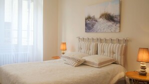 A bedroom with a bed, two bedside lamps, a painting on the wall, and a window with sheer curtains. - Beautiful private villa for 2 guests with WIFI, TV and terrace (Cancale)