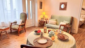 A cozy dining area with a round table set for two, a green sofa, and a wooden chair. - Beautiful private villa for 2 guests with WIFI, TV and terrace (Cancale)